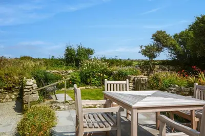 a wooden table and chairs in a garden at 2 Bed in Rinsey oc-2chapl in Praa Sands