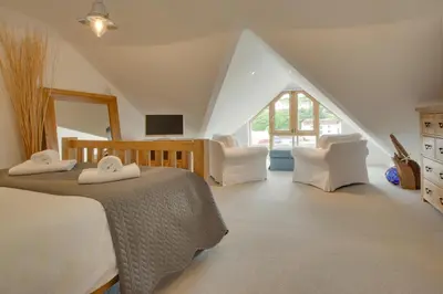 a bedroom with a bed and two white chairs at 2 Bed in Porthleven oc-4stelv in Porthleven