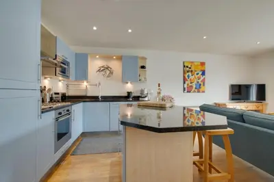 a kitchen with white cabinets and a kitchen island with a couch at 2 Bed in Porthleven oc-4stelv in Porthleven