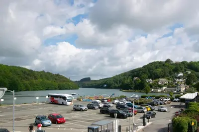 a parking lot with cars parked next to a river at 2 Bed in Looe oc-6creek in Looe