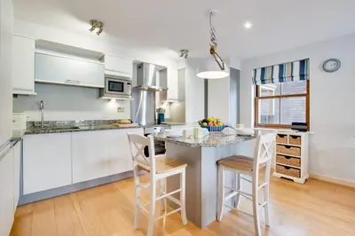 a kitchen with white cabinets and a island with bar stools at 2 Bed in Looe oc-6creek in Looe