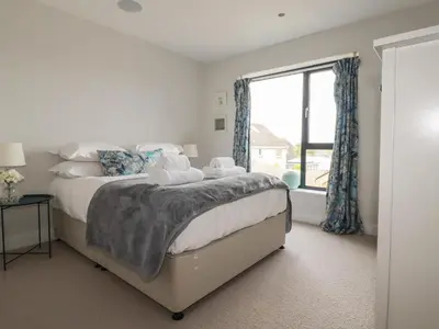 a bedroom with a bed and a large window at 5 Longshore in Newquay