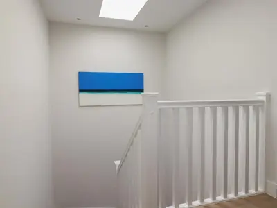 a white staircase with a blue painting on the wall at 5 Longshore in Newquay