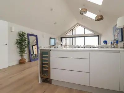 a kitchen with white cabinets and a large window at 5 Longshore in Newquay