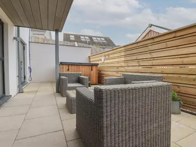 a patio with wicker chairs and a wooden fence at 5 Longshore in Newquay