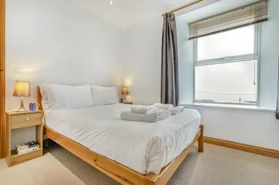 a bedroom with a bed with white sheets and a window at 3 Bed in Porthleven oc-atlant in Porthleven