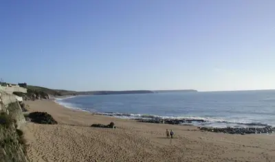 a beach with two people walking on the sand at 3 Bed in Porthleven oc-atlant in Porthleven
