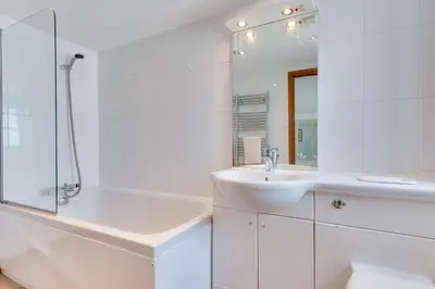 a white bathroom with a sink and a mirror at 3 Bed in Falmouth oc-anchge in Falmouth