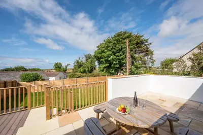 a patio with a wooden table and chairs on a deck at 3 Bed in Higher Crackington oc-avond in Crackington Haven