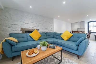 a living room with a blue couch and yellow pillows at Burrow Cottage in St Ives