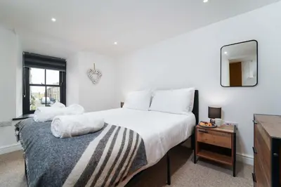a bedroom with a bed and a mirror and a table at Burrow Cottage in St Ives