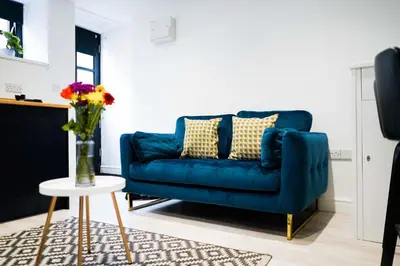 a blue couch in a living room with a vase of flowers at Little Burrows in St Ives