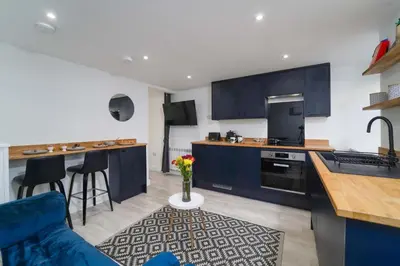 a kitchen with blue cabinets and a blue couch at Little Burrows in St Ives