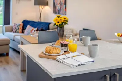 a breakfast table with a plate of croissants and orange juice at 3 Bed in Penrose oc-butcup in Saint Ervan