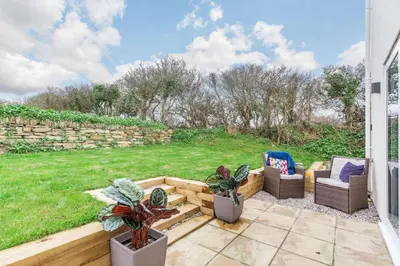 a patio with two chairs and a stone wall at 3 Bed in Penrose oc-butcup in Saint Ervan