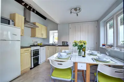 a kitchen with a table and chairs and a white refrigerator at 2 Bed in Fowey oc-ccgree in Fowey