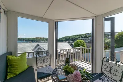 a balcony with two chairs and a table and windows at 2 Bed in Fowey oc-ccgree in Fowey