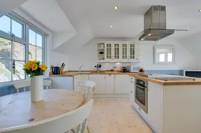 a kitchen with a wooden table and a vase with flowers at 2 Bed in Porthleven oc-clifto in Porthleven