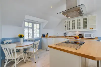 a kitchen with white cabinets and a table and chairs at 2 Bed in Porthleven oc-clifto in Porthleven