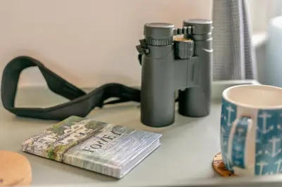 a gun and a book on a counter with a cup at 4 Bed in Fowey oc-chview in Fowey