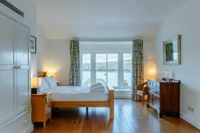 a bedroom with a bed and a desk and a window at 5 Bed in Polruan oc-ccmead in Fowey