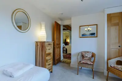a bedroom with a bed and a mirror and a chair at 5 Bed in Polruan oc-ccmead in Fowey