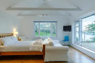 a bedroom with a bed and a couch and windows at 5 Bed in Polruan oc-ccmead in Fowey