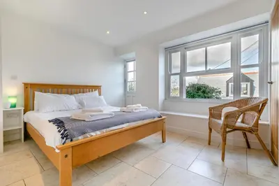 a bedroom with a bed and a chair and a window at 2 Bed in Polruan oc-cgart2 in Fowey