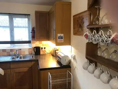 a kitchen with cups on the wall and a sink at Cosy 3 Bedroom House on Cornish estate with pool in Bodmin