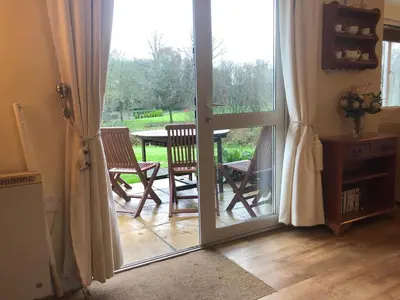 an open door to a patio with a table and chairs at Cosy 3 Bedroom House on Cornish estate with pool in Bodmin
