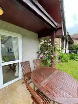 a wooden table and two chairs on a patio at Cosy 3 Bedroom House on Cornish estate with pool in Bodmin