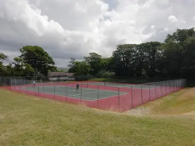 a tennis court with two tennis players on it at Cornwall family friendly villa with free use of Pool, soft play, mini golf, tennis, gym, fitness classes, sauna and ice baths in Newquay