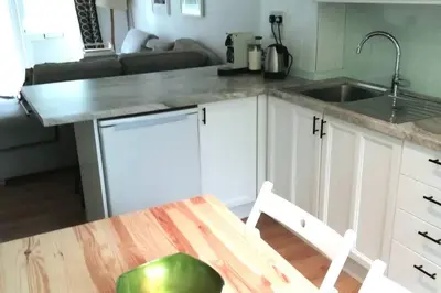 a kitchen with white cabinets and a sink and a table at Cornwall family friendly villa with free use of Pool, soft play, mini golf, tennis, gym, fitness classes, sauna and ice baths in Newquay