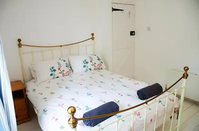 a white bed with flowers on it in a room at Lovely cottage with private garden in Penryn