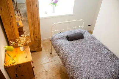 a small bedroom with a bed and a table at Lovely cottage with private garden in Penryn