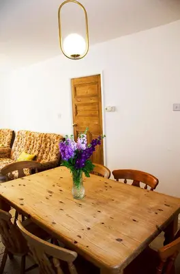a wooden table with a vase of flowers on it at Lovely cottage with private garden in Penryn