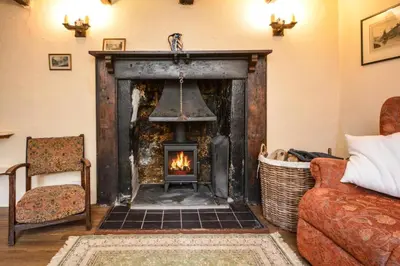 a living room with a fireplace and a chair at 3 Bed in Lostwithiel oc-cmerl in Saint Winnow
