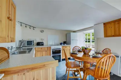a kitchen with a wooden table and a table and chairs at 3 Bed in Lostwithiel oc-cmerl in Saint Winnow