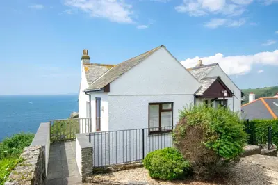 a white house with the ocean in the background at 4 Bed in Fowey oc-cridg2 in Fowey
