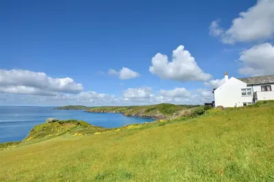 a white house on a hill next to the ocean at 4 Bed in Fowey oc-cridg2 in Fowey