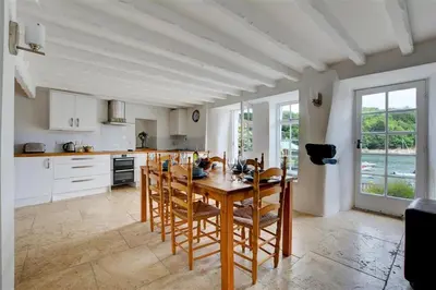 a large kitchen with a wooden table and chairs at 3 Bed in Fowey oc-cstepa in Fowey