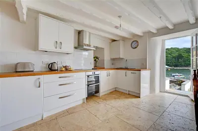 a kitchen with white cabinets and a large window at 3 Bed in Fowey oc-cstepa in Fowey