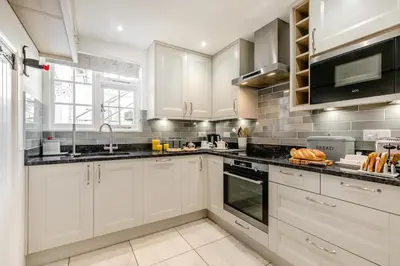 a kitchen with white cabinets and black counter tops at 3 Bed in Helford oc-dowrpe in Helford