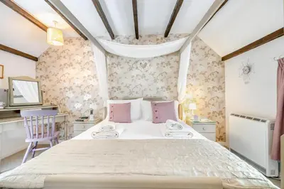a bedroom with a large bed with pink pillows at 3 Bed in Helford oc-dowrpe in Helford