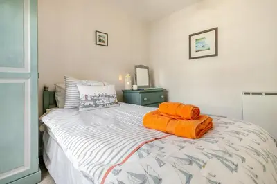 a bedroom with a bed with orange towels on it at 3 Bed in Helford oc-dowrpe in Helford