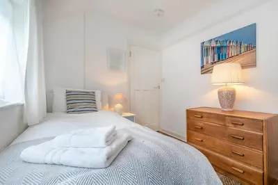 a bedroom with a bed with white sheets and a dresser at 4 Bed in Pentewan oc-edghil in Pentewan