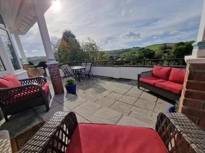 a patio with a red couch and a table and chairs at 4 Bed in Pentewan oc-edghil in Pentewan