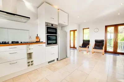 a kitchen with white cabinets and two chairs at 4 Bed in Marazion oc-gwynsa in Marazion