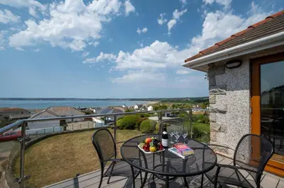 a table and chairs on a balcony with a view of the ocean at 4 Bed in Marazion oc-gwynsa in Marazion
