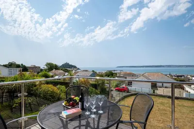 a table and chairs on a balcony with a view of the ocean at 4 Bed in Marazion oc-gwynsa in Marazion